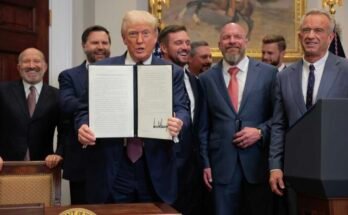 Trump muestra un decreto firmado, rodeado de funcionarios y atletas profesionales.