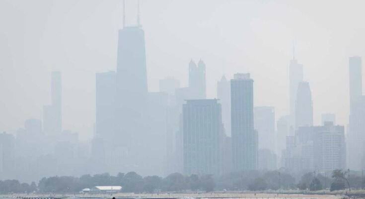 La gente se estremece en la hierba frente al lago en el lado norte como una niebla de los bosques fumadores canadienses en la región de Chicago y crea mala calidad del aire el jueves 31 de julio de 2025.