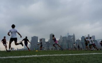 La gente juega al rugby en el clima brumoso en Brooklyn Bridge Park el 27 de julio de 2025 en Nueva York. Las condiciones de descarga y un aviso de humo fueron causados por el humo después de un incendio forestal en Canadá.