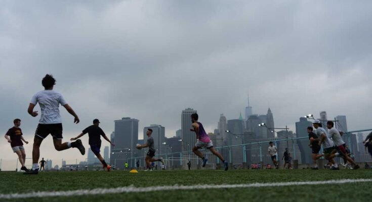 La gente juega al rugby en el clima brumoso en Brooklyn Bridge Park el 27 de julio de 2025 en Nueva York. Las condiciones de descarga y un aviso de humo fueron causados por el humo después de un incendio forestal en Canadá.