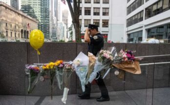 NUEVA YORK, Nueva York - 29 de julio: un oficial de policía de Nueva York pasa frente a flores colocadas frente al edificio de oficinas del centro de la ciudad, donde un hombre armado mató a cuatro personas el 29 de julio de 2025 en Nueva York. (Foto de Stephanie Keith / Getty Images)