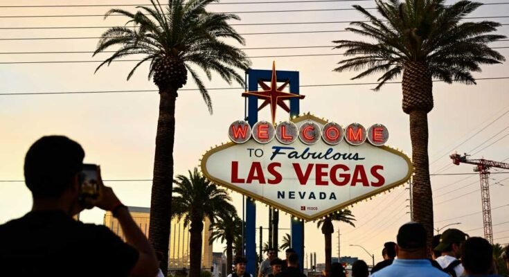 La gente toma fotos con la recepción del fabuloso panel de Las Vegas bajo un cielo naranja nebuloso mientras el sol se pone el 29 de julio de 2023.