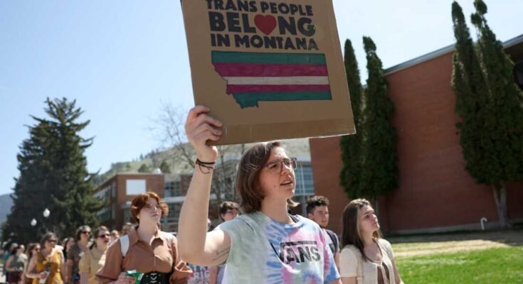 Los activistas de los derechos transgénero tienen señales mientras cruzan el campus de la Universidad de Montana el 03 de mayo de 2023 en Missoula, Mont.